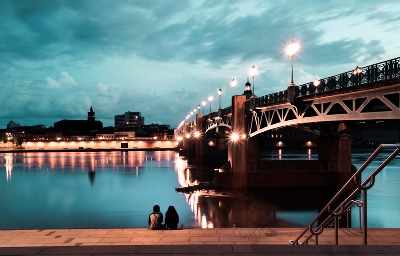 couple sitting by the river under the bridge at su Z5ZAMC9 1