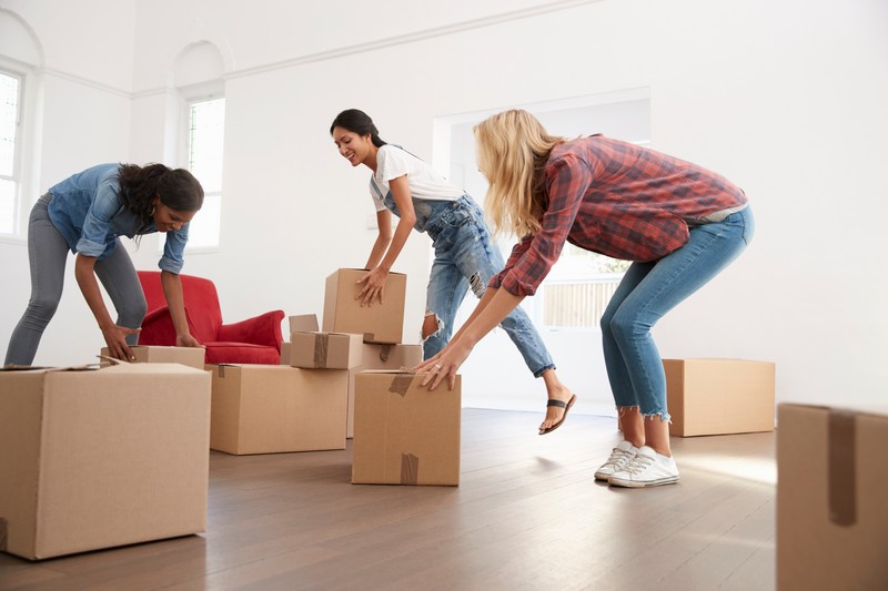 three female friends carrying boxes into new home PYMEKPL 1